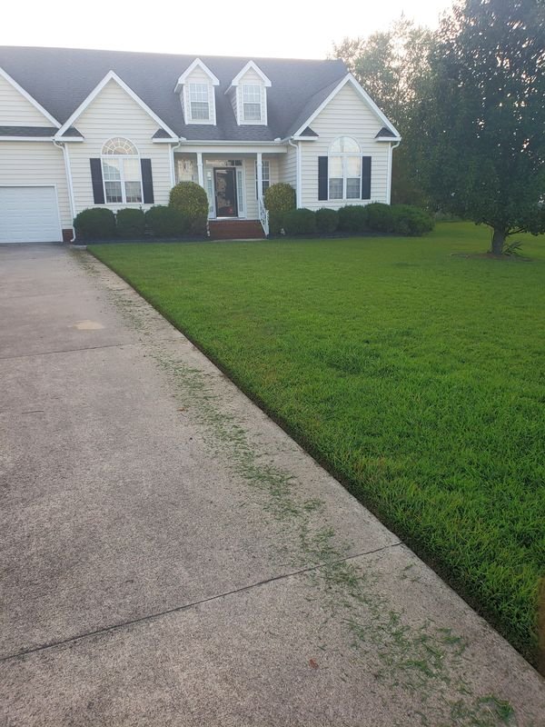 A cream-colored house with a freshly cut lawn and edged driveway