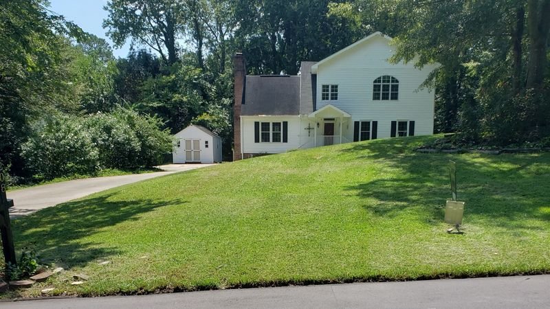 A white house on a hill with a freshly cut lawn
